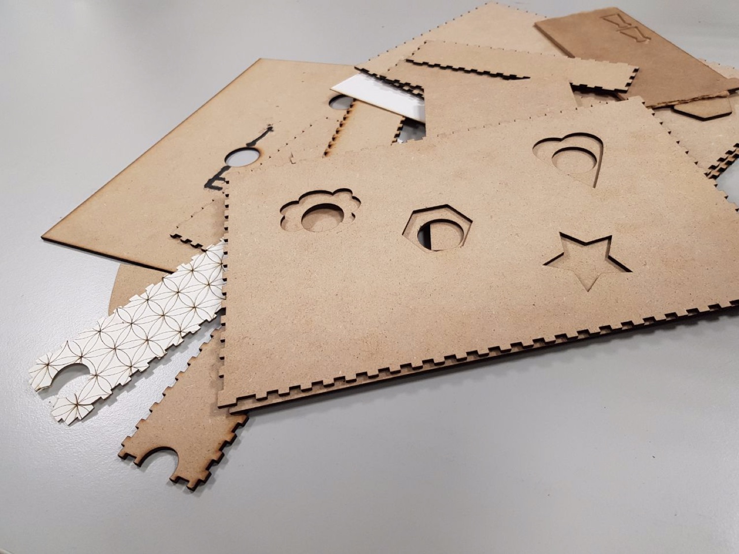 Laser-cut MDF panels with flower, hexagon, heart, and star stencil cutouts, plus patterned keychain blanks